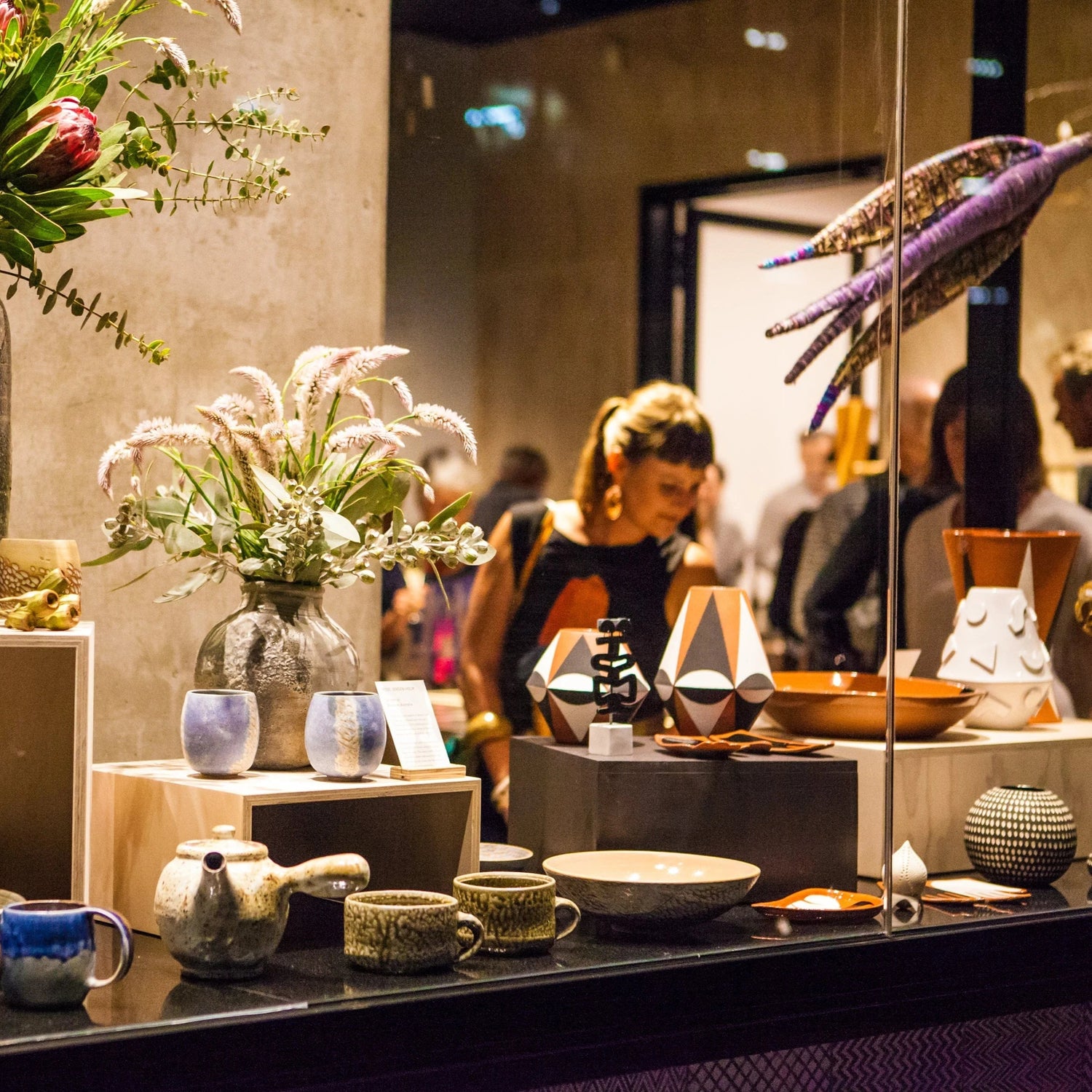 View through glass window of interior of artisan gift store with people browsing the shop