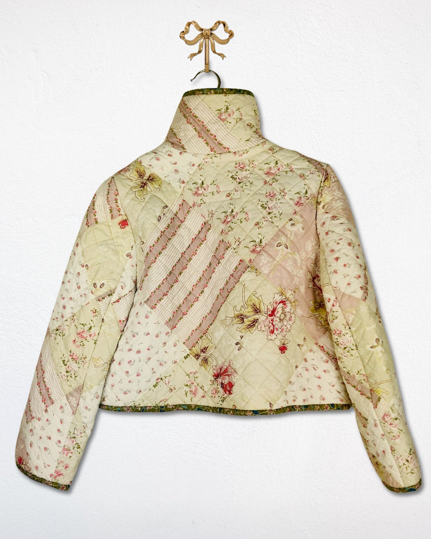 Back view of a handmade foral quilted jacket on a white background