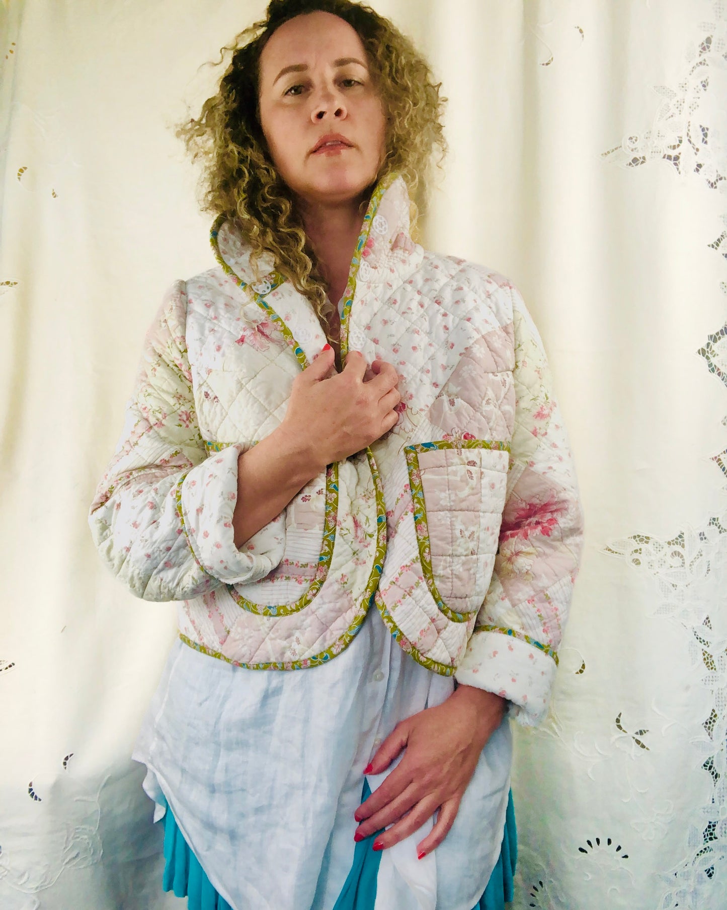 Woman wearing a floral quilted jacket against a white curtain background