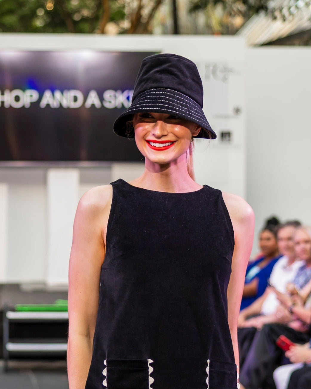 Model on runway wearing matching corduroy shift dress and bucket hat