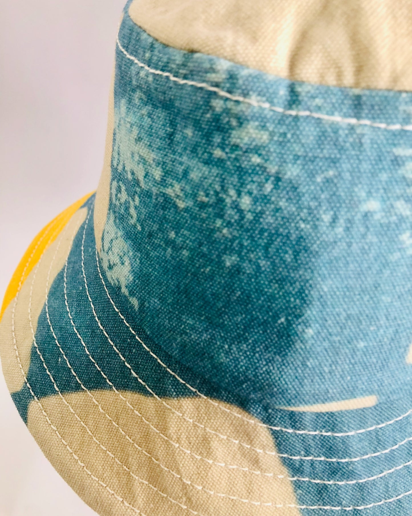 Close up detail of blue and white bucket hat showing top stitch feature