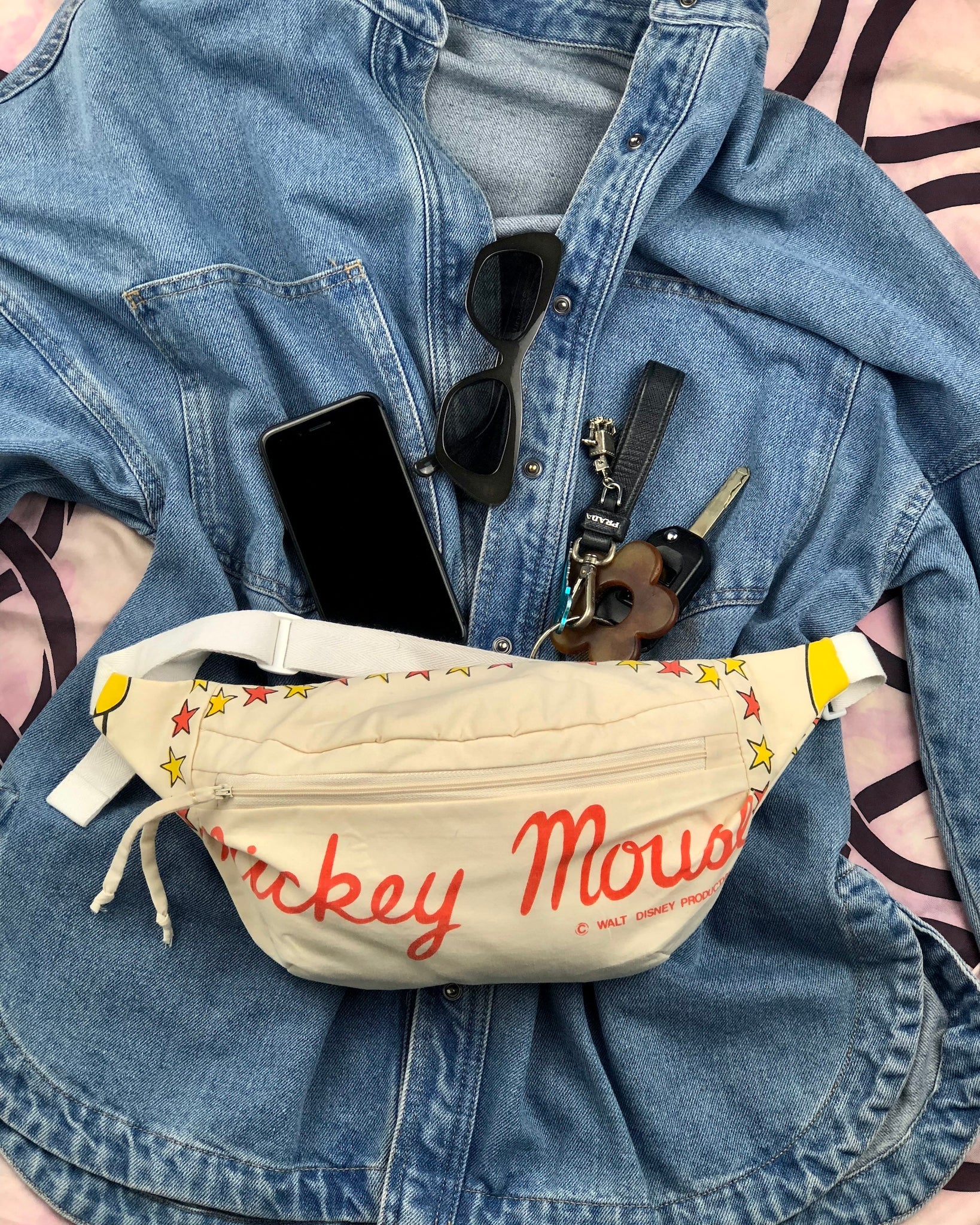 Flay lay showing how to style mickey mouse hand made bum bag with a basics denim shirt and sunglasses