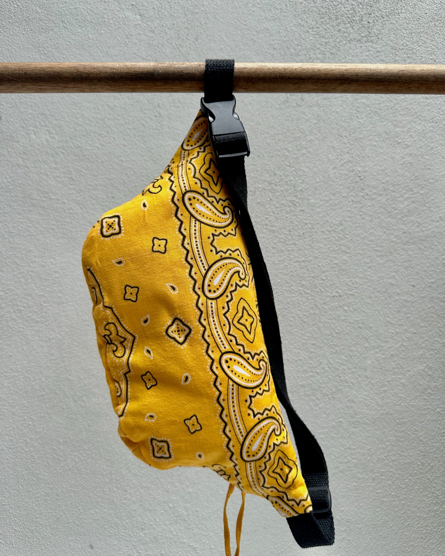 Yellow bandana-patterned bag with a black strap on a gray background