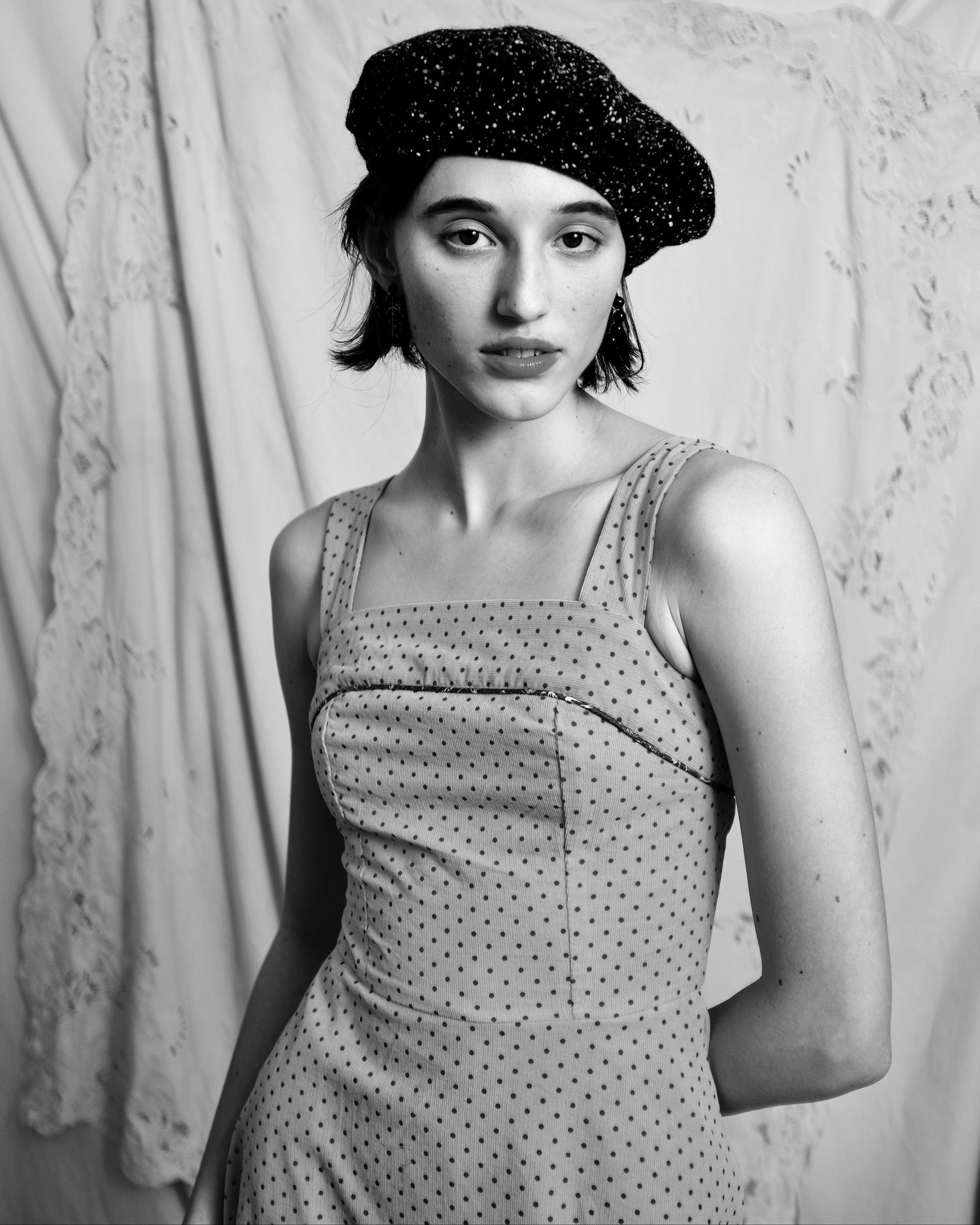 black and white photo of young woman wearing a fit and flare corduroy dress and wearing black beret