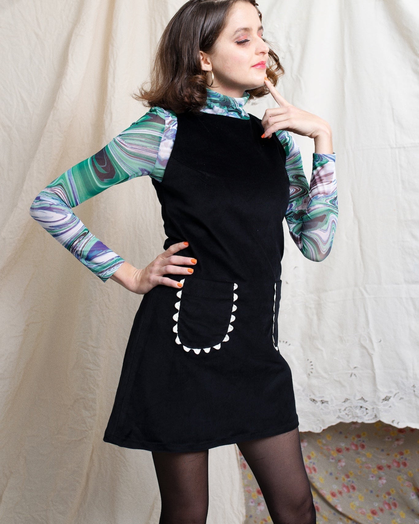 Girl wearing a corduroy little black dress over a sixties style turtleneck and black thights