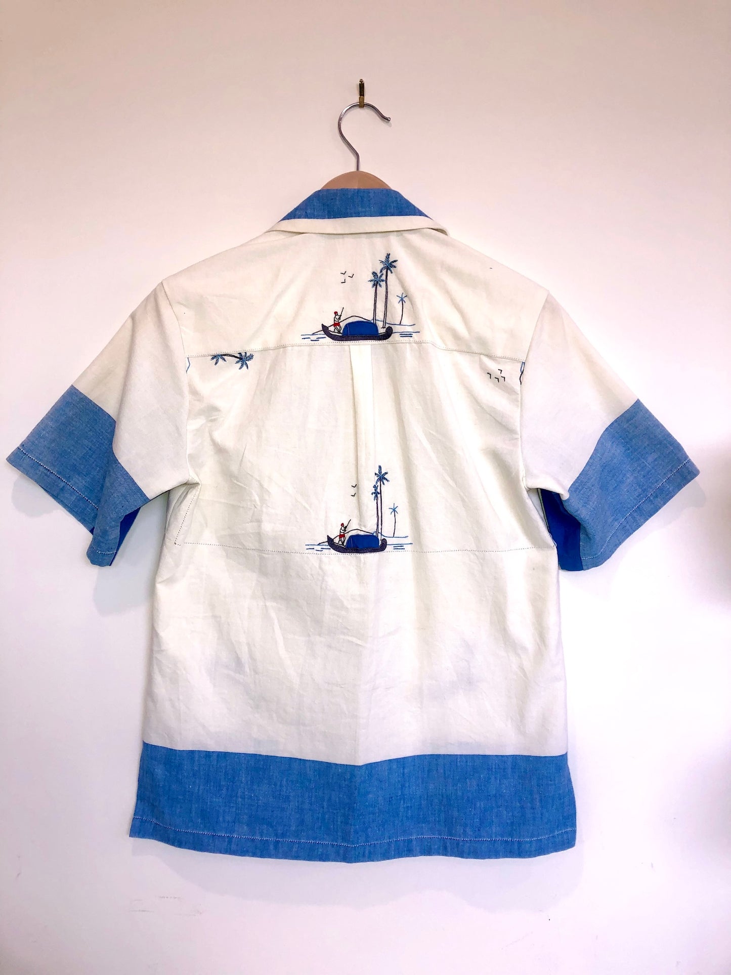 White shirt with blue accents and graphics on a hanger against a white background