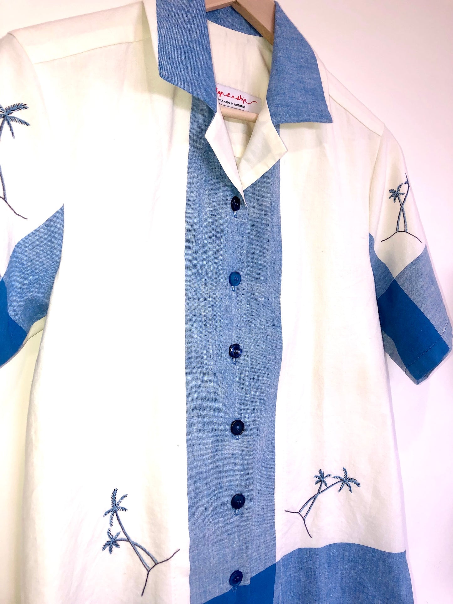 White shirt with blue accents and palm tree designs on a white background