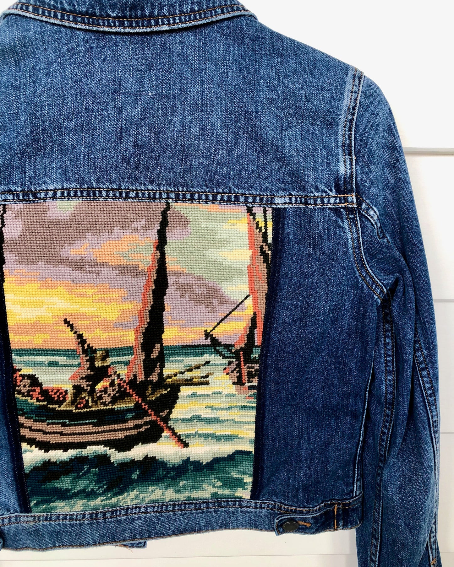 Close up detail of needle point embroidery decorating the back panel of a pre loved Diesel denim jacket