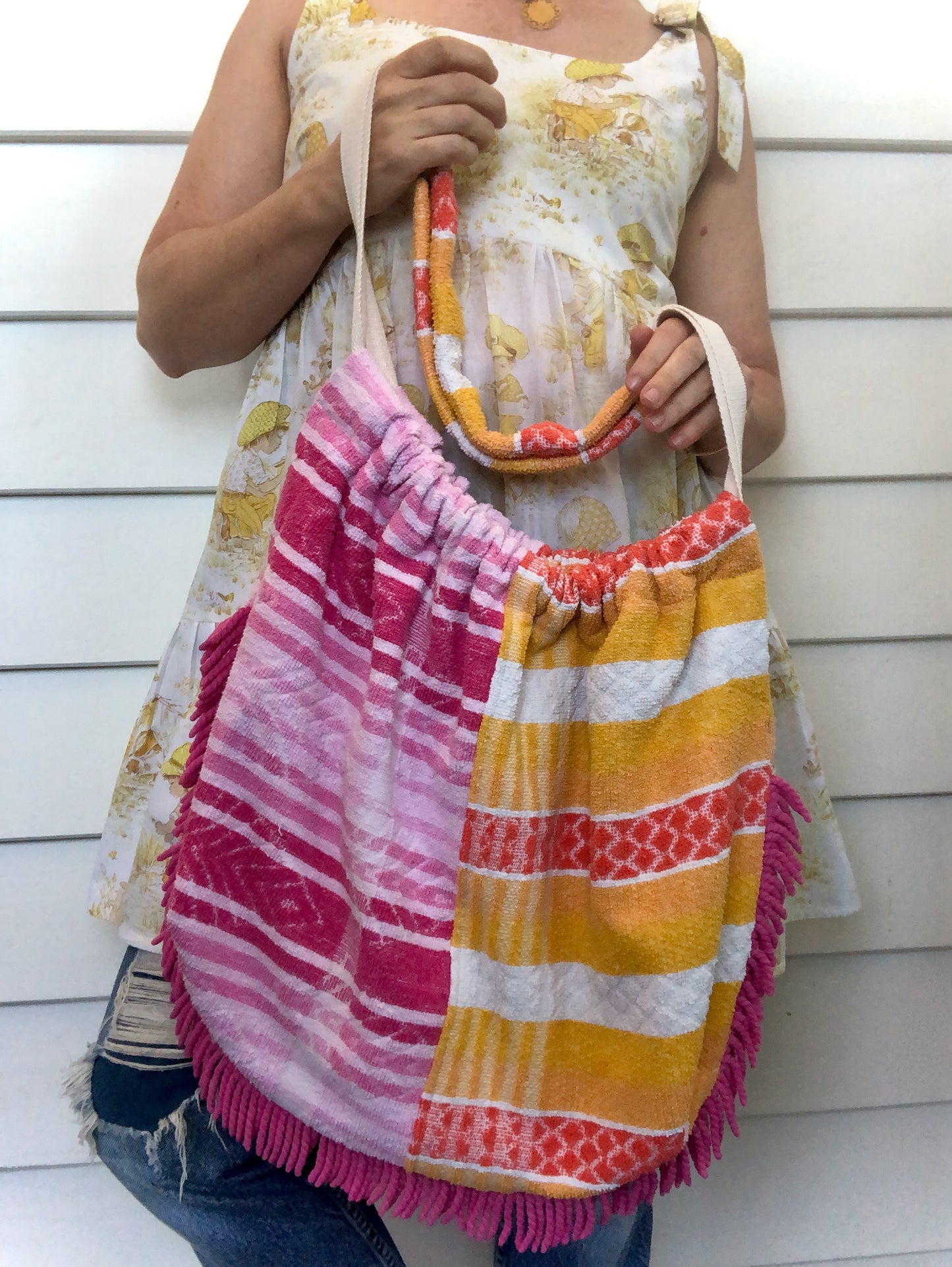 Woman holding beach bag made from pink and orange toweling with bright pink fringing