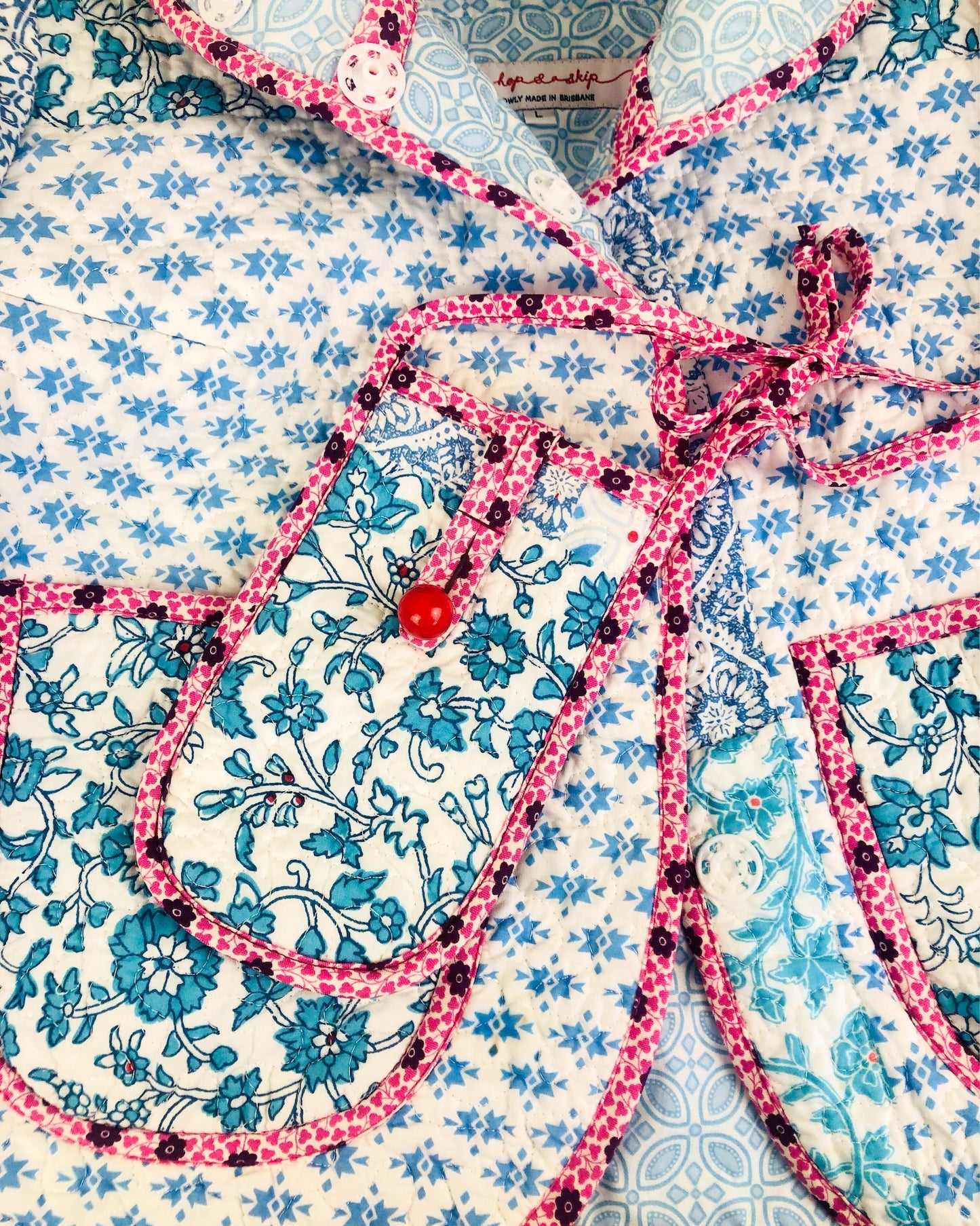 Close-up of a floral patterned fabric with a pink liberty of london bias binding  and red bead vintage button.