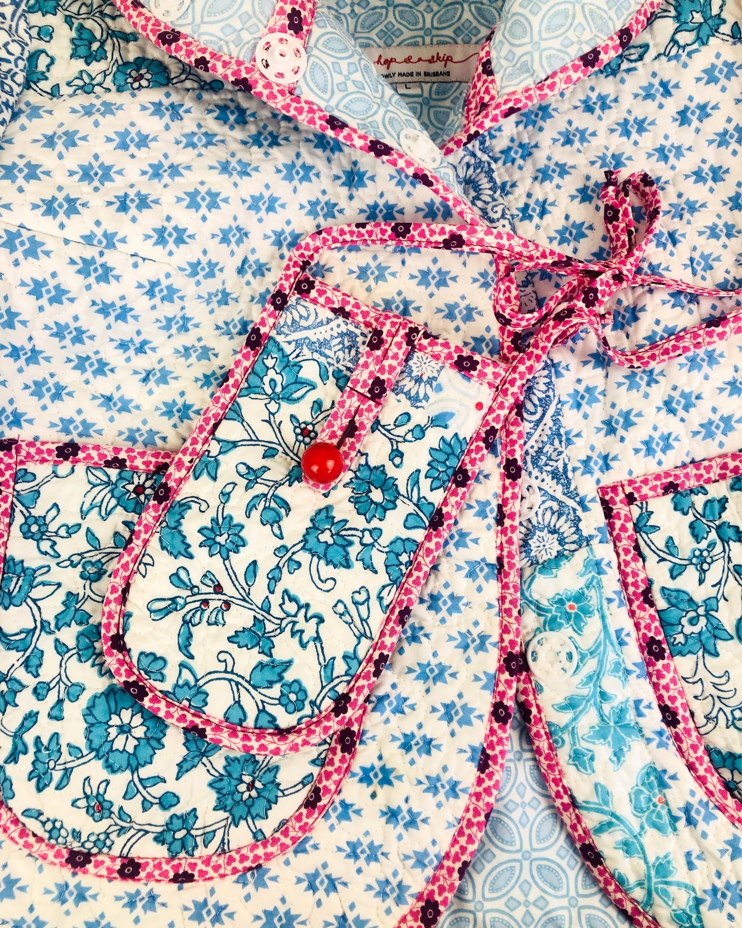Close-up of a floral patterned fabric with a pink liberty of london bias binding  and red bead vintage button.