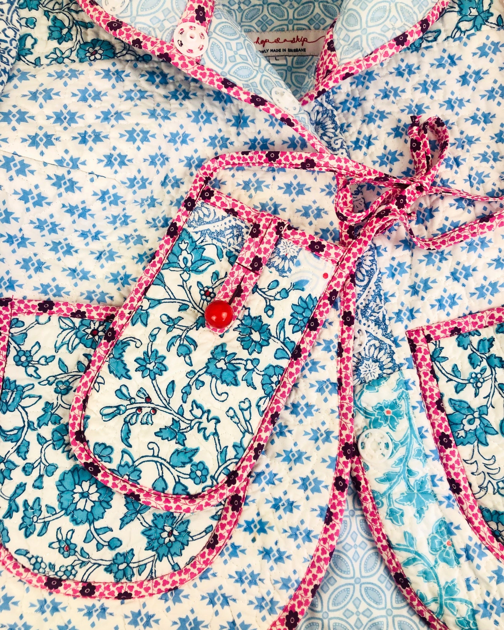 Close-up of a floral patterned fabric with a pink liberty of london bias binding  and red bead vintage button.