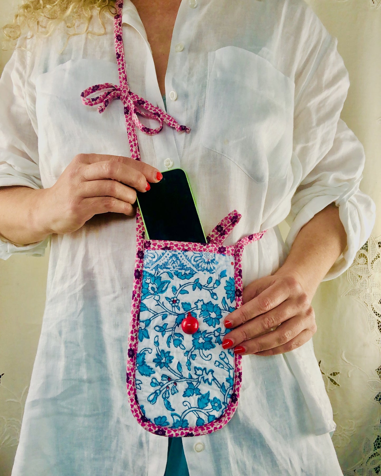 Person holding a quilted phone case with floral design and pink liberty of london trim.
