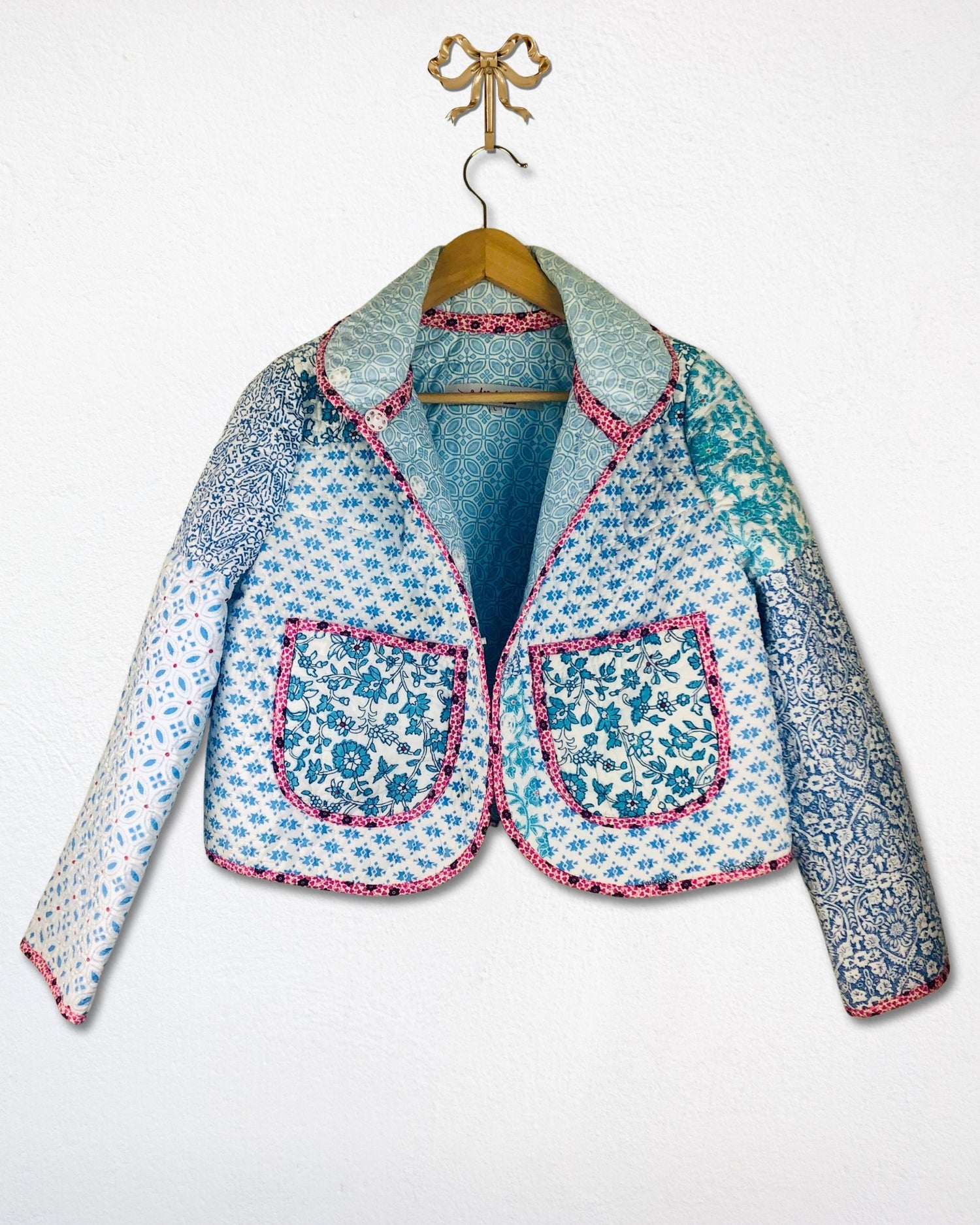 Floral patterned handmade jacket on a hanger against a white background