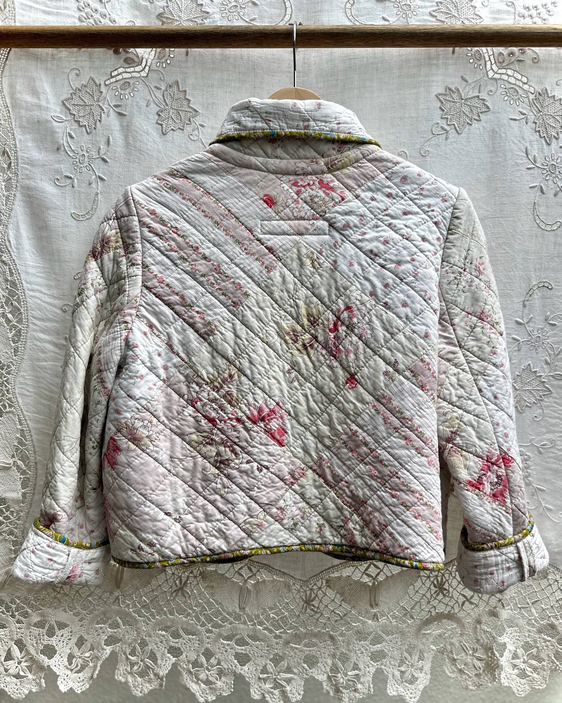 Back view of a quilted jacket with floral patterns on an embroidered linen background