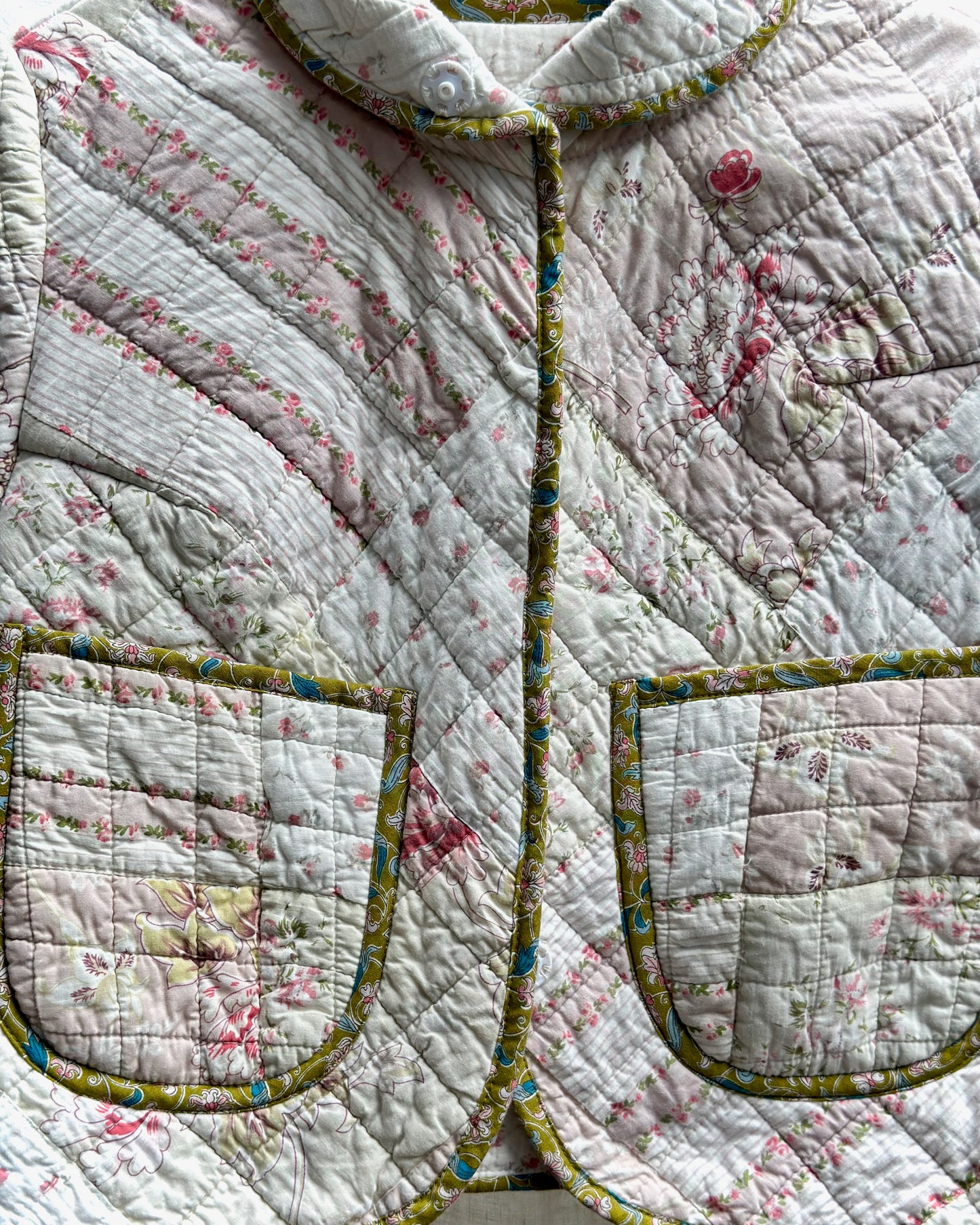Quilted jacket with floral pattern and green trim bias binding made from liberty of london fabric on a white background