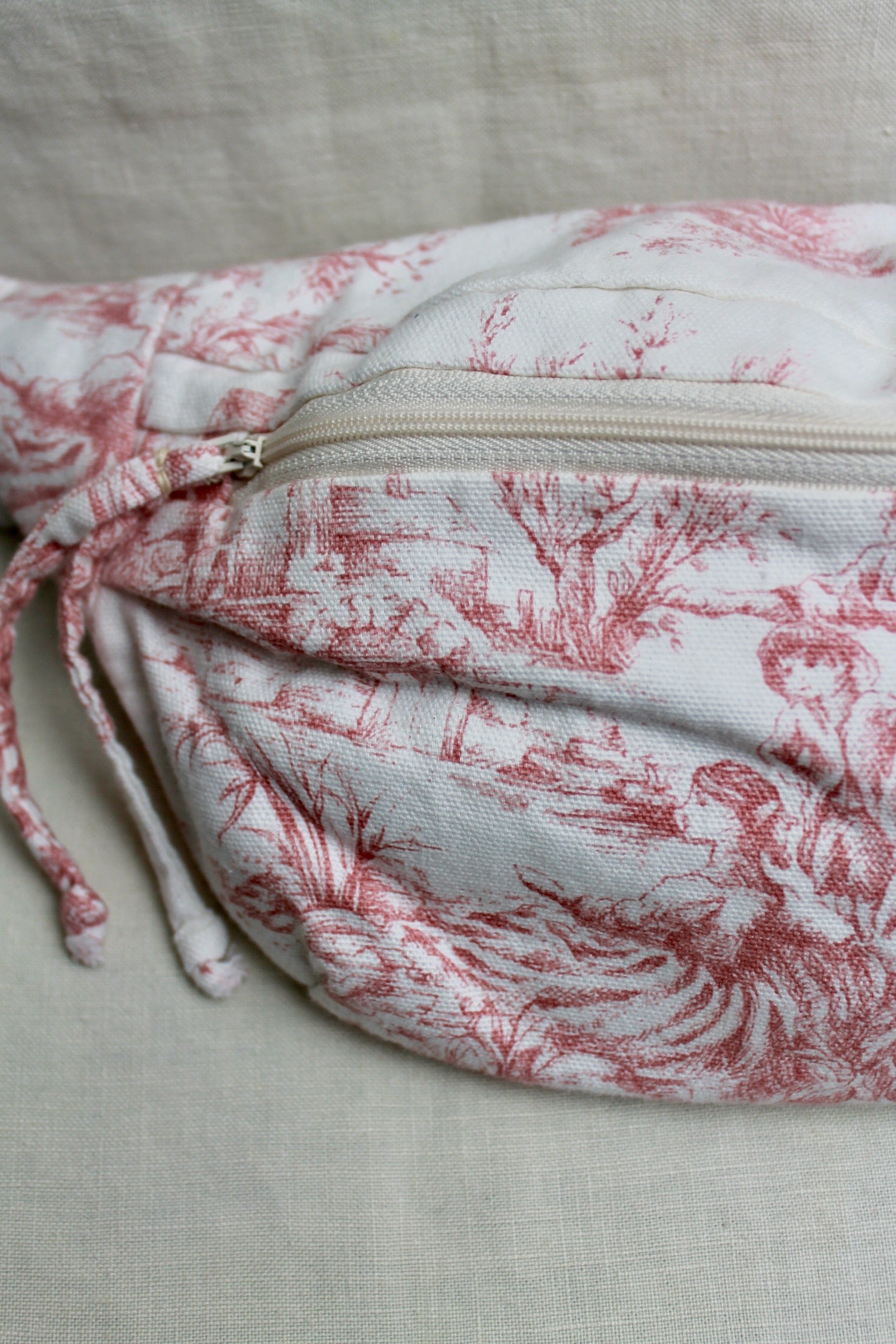 Close up view of upcycled bumbag made from a pink and white toile du jouy thrifted fabric