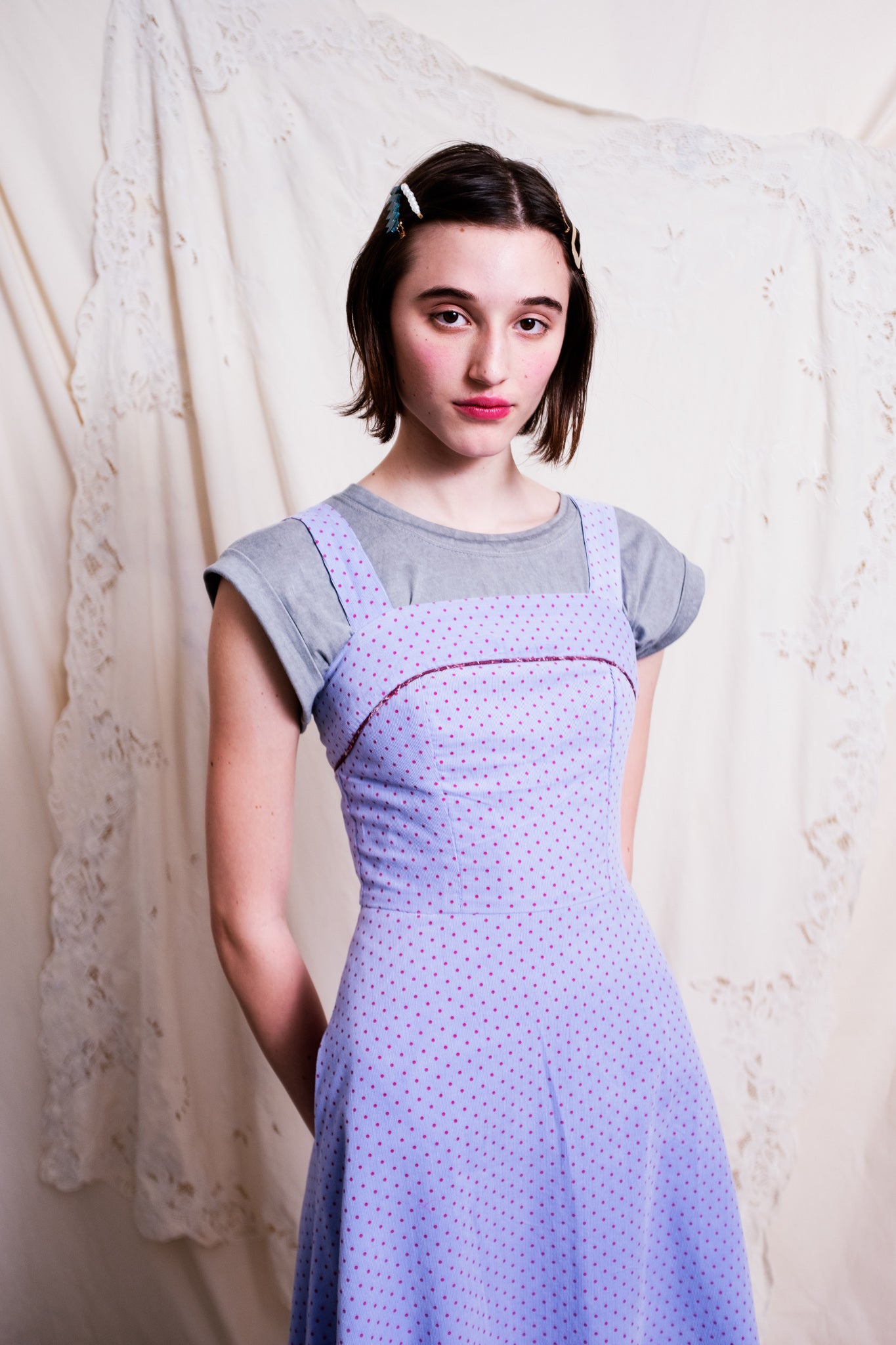 Close up of woman wearing a pinwale corduroy dress posing with her hands behind her back