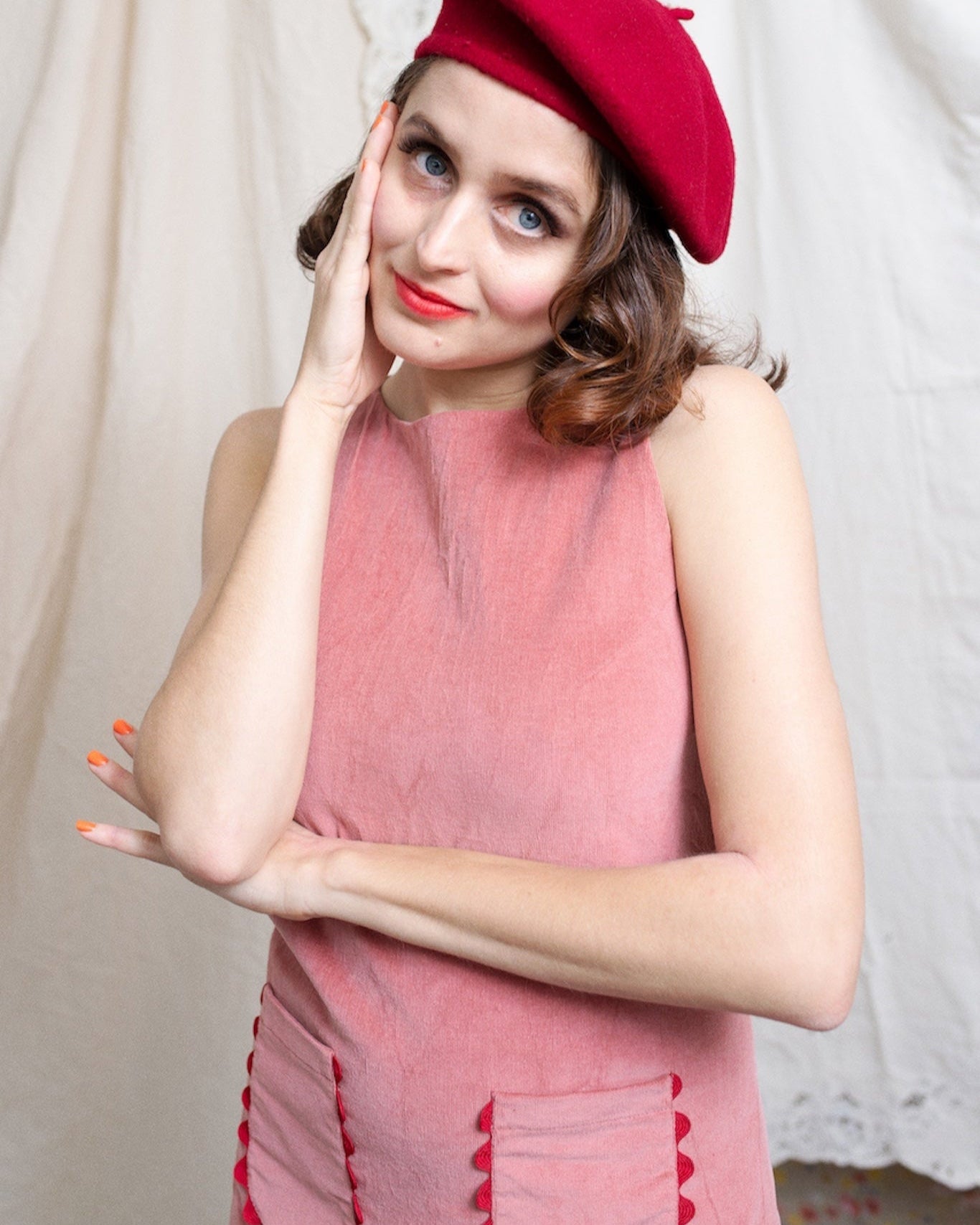 Model wearing a dusty pink corduroy shift dress with a red beret