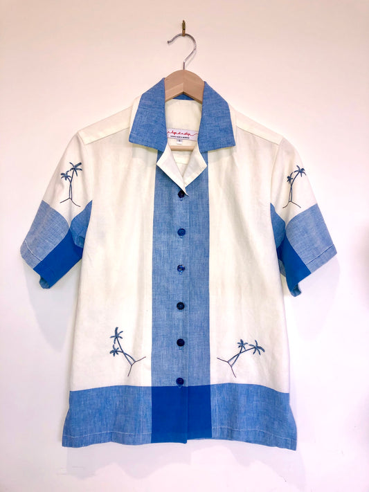 White shirt with blue accents on a hanger against a white background
