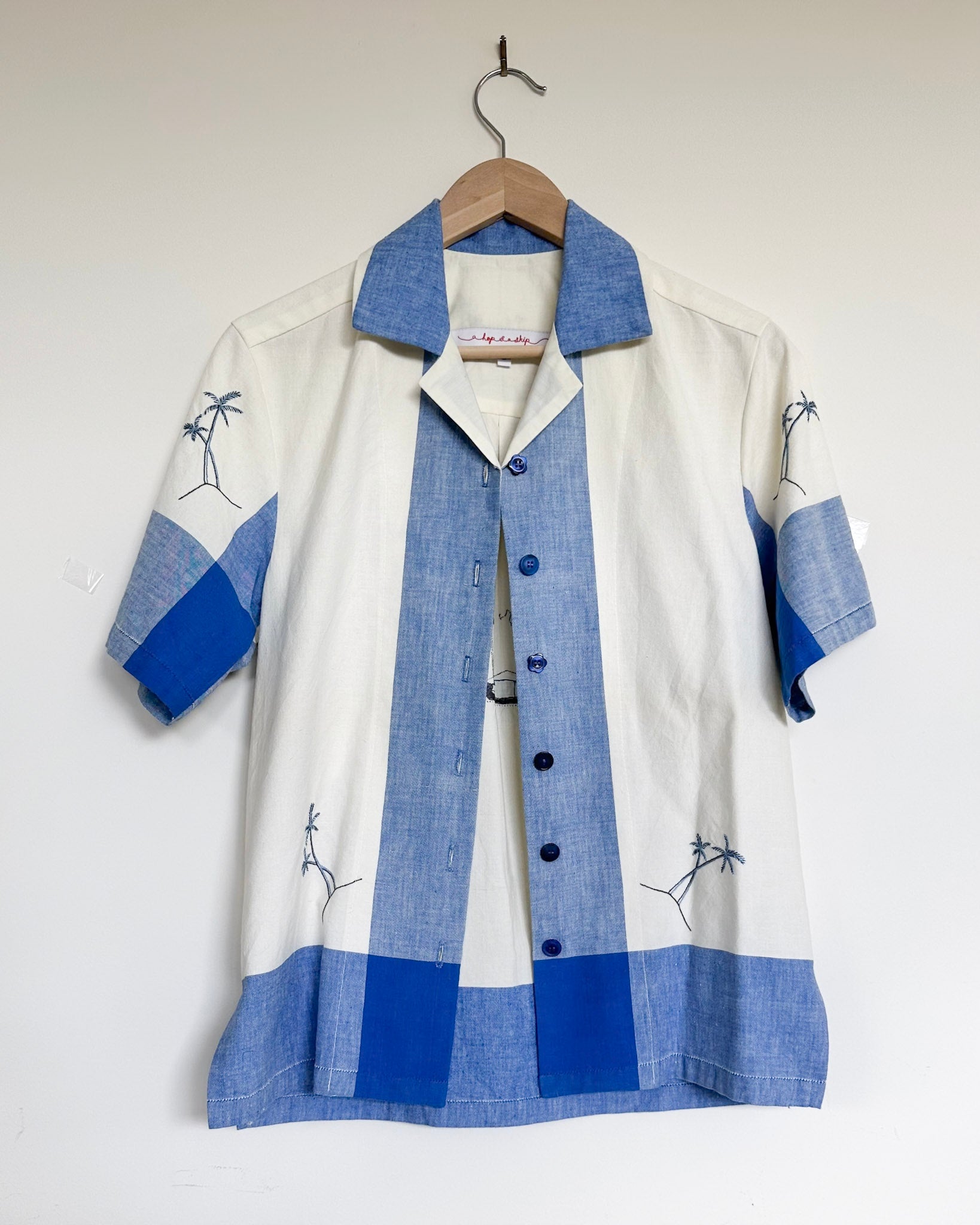 White shirt with blue accents on a hanger against a white background