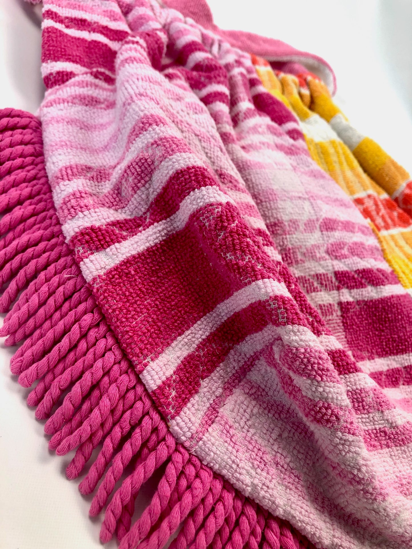 Close up detail of bright pink and orange beach bag with towelling fringing