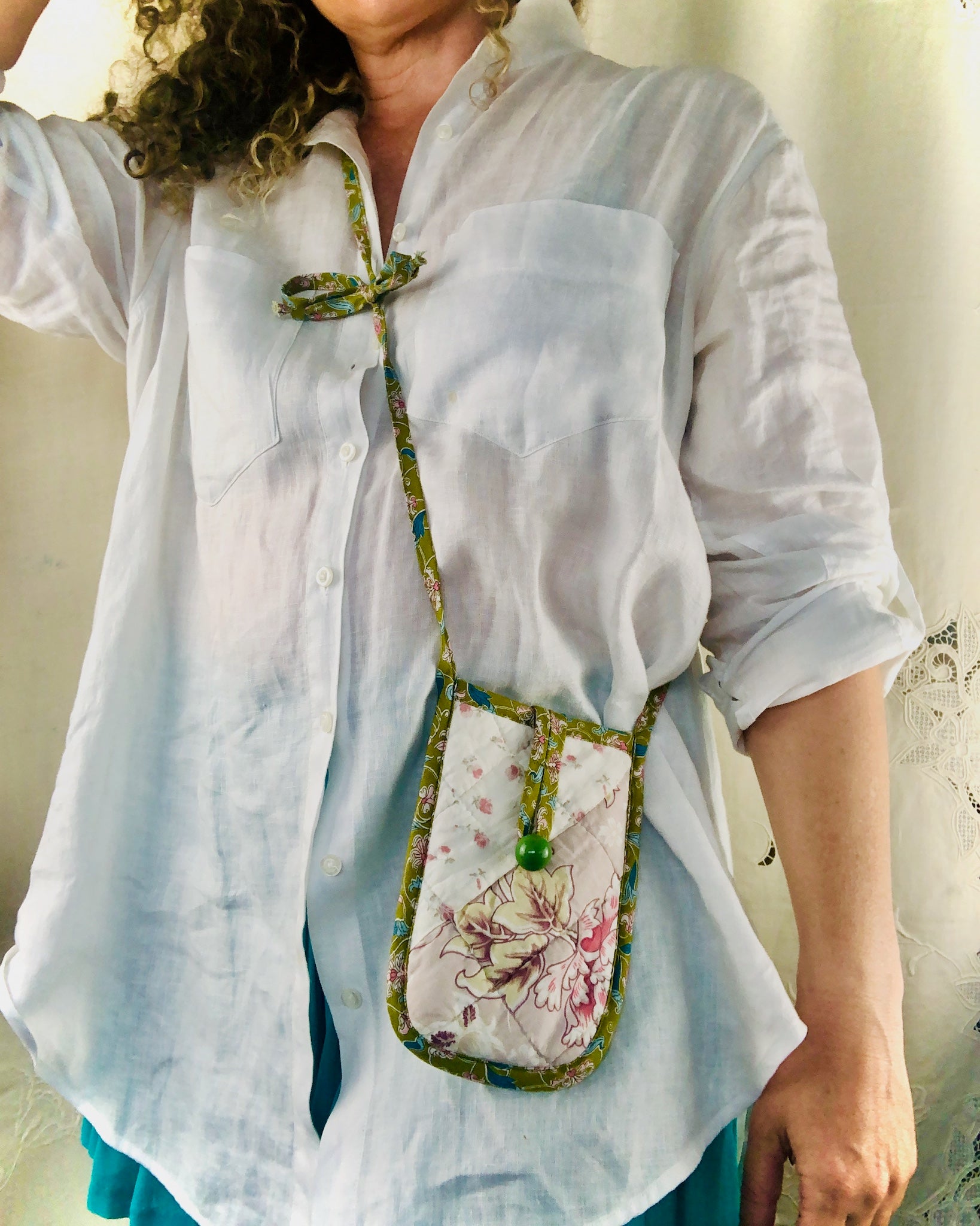 Woman wearing a white shirt with a floral crossbody bag.