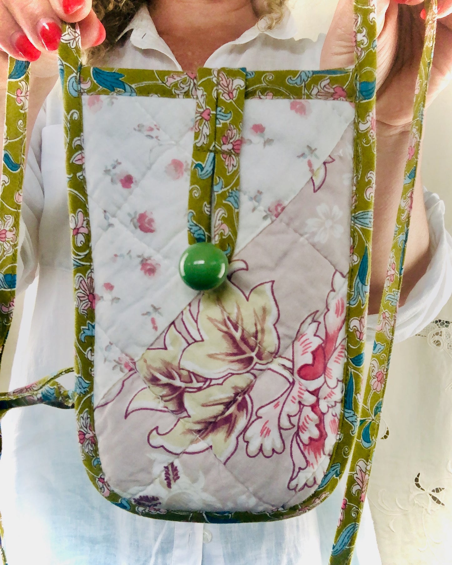 Floral-patterned phone pouch held by a person with a white shirt