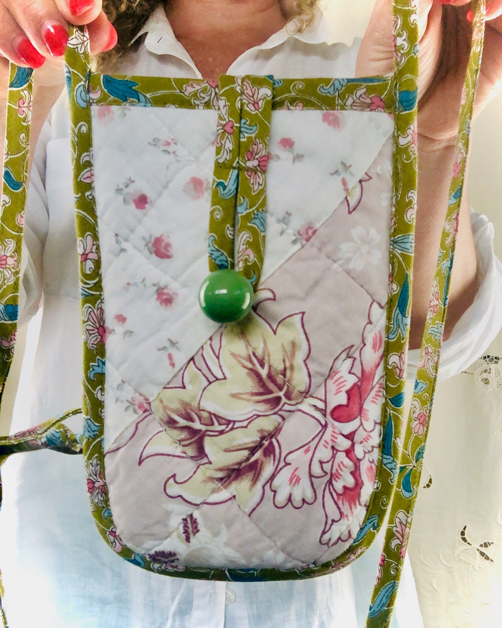 Floral-patterned phone pouch held by a person with a white shirt