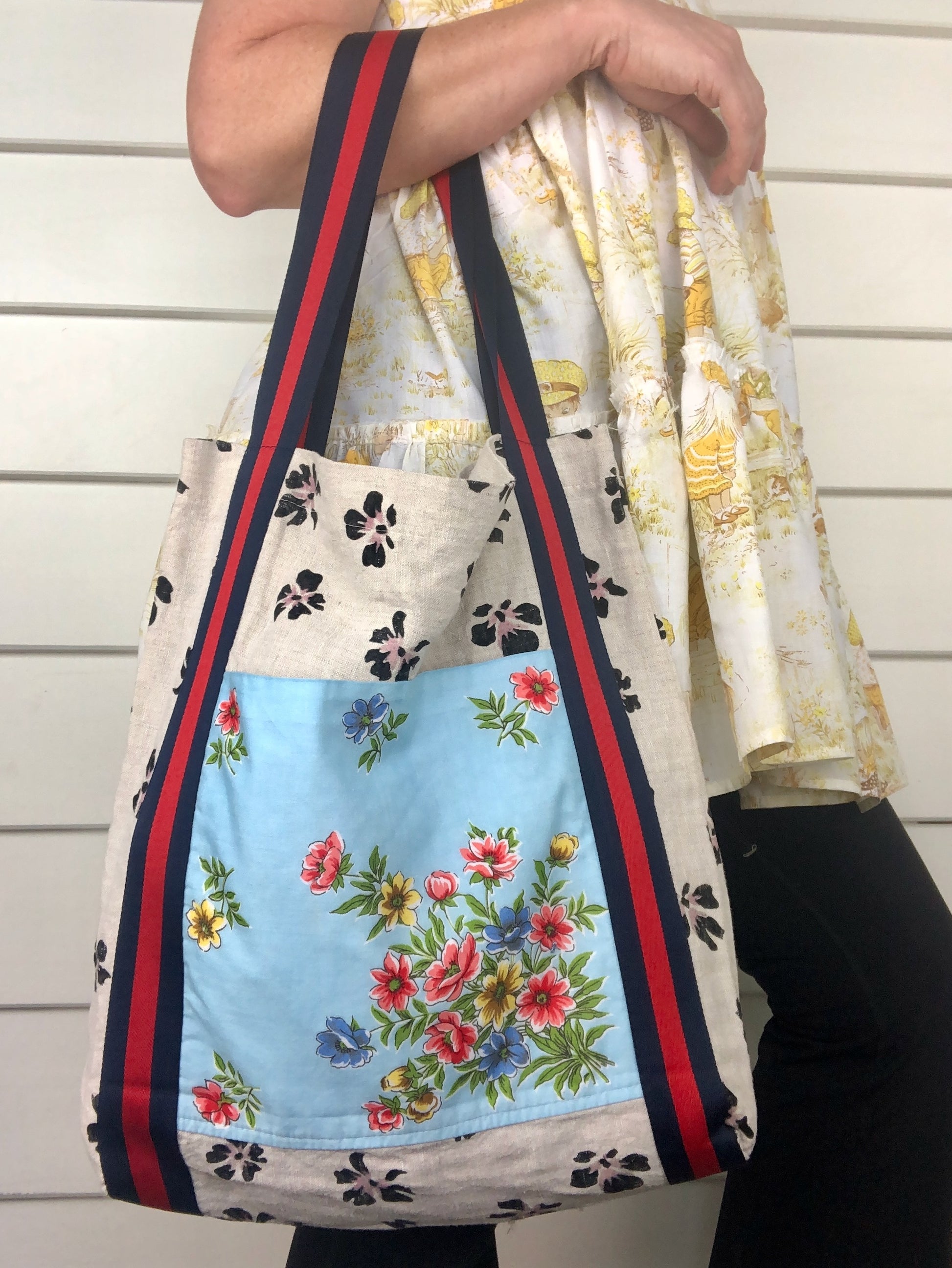 Woman wearing a yellow floral dress and an eclectic floral and striped strap tote bag