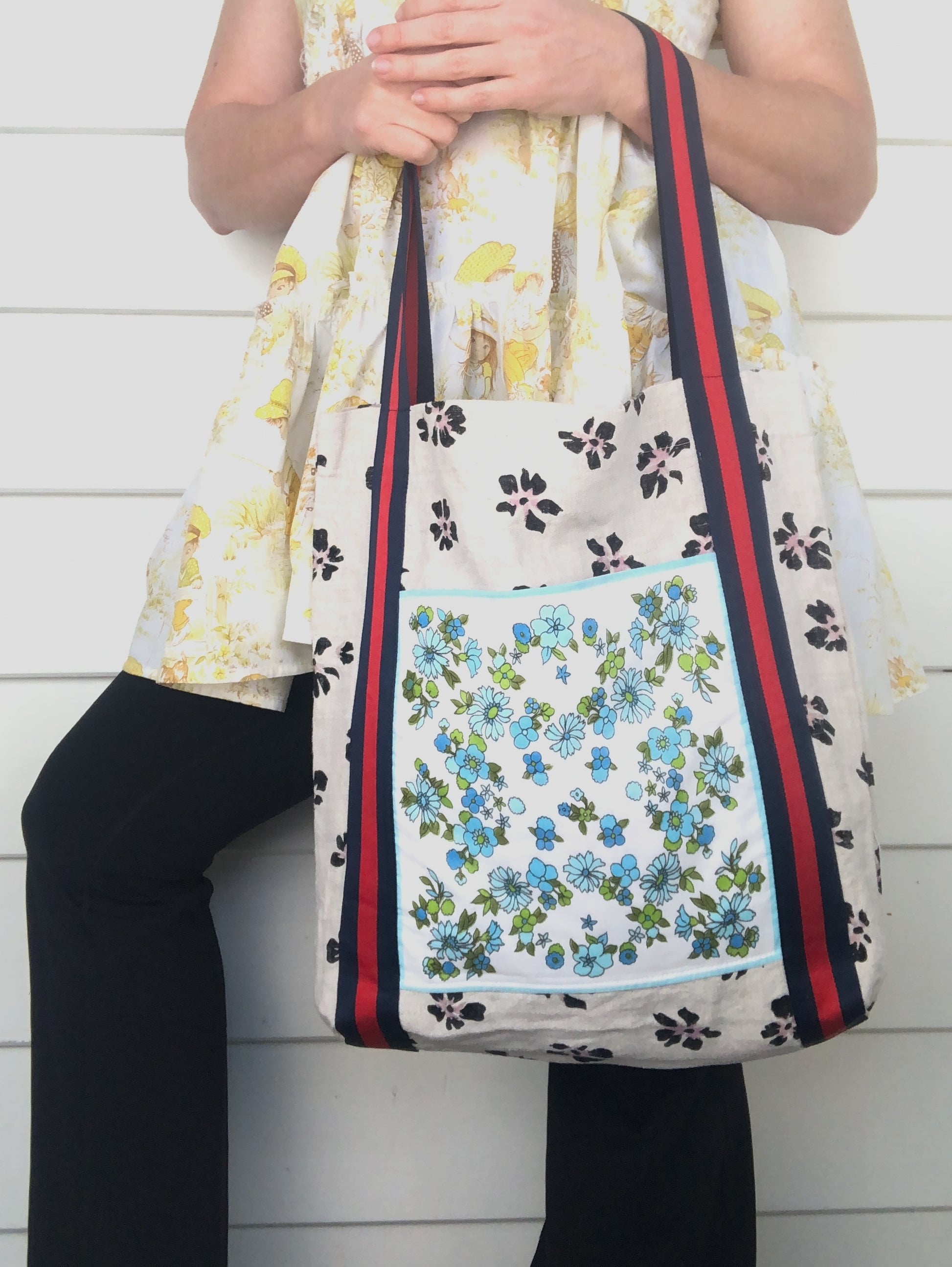 Woman with a yellow babydoll dress holding a unique floral tote bag with striped straps